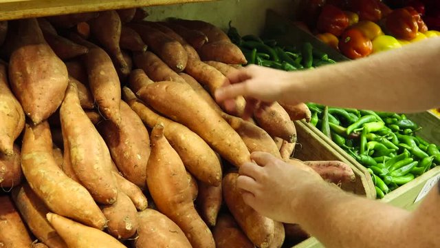 A Caucasian guy buying sweet potatoes (yams) at the grocery store for his healthy high fibre diet