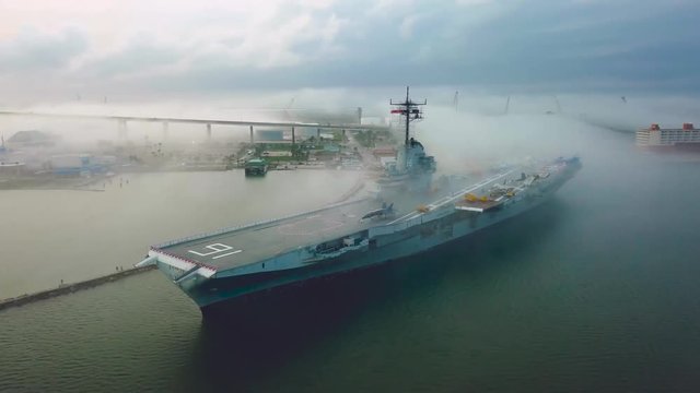Drone flying around aircraft carrier in Corpus Christi looking at the front of the flight deck in the fog that passes over the navy ship stuck on a sandbar in the gulf.