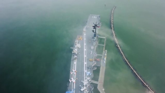 Drone flying over aircraft carrier in Corpus Christi looking down on the flight deck in the fog that passes over the navy ship stuck on a sandbar in the gulf.