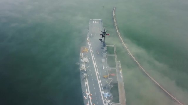 Drone flying over aircraft carrier in Corpus Christi looking down on the flight deck in the fog that passes over the navy ship stuck on a sandbar in the gulf.