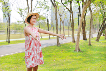 Young Asian woman raising arms and smile in nature park.