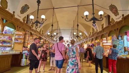 KRAKOW, POLAND - JUNE 11, 2018: Walk along the crowded medieval gallery of the Cloth Hall with many handicraft stalls and souvenir shops, on June 11 in Krakow