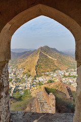 Ancient long wall with towers around Amber Fort through the arch of tower walls. Rajasthan. India