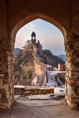 Ancient long wall with towers around Amber Fort through the arch of tower walls at morning....