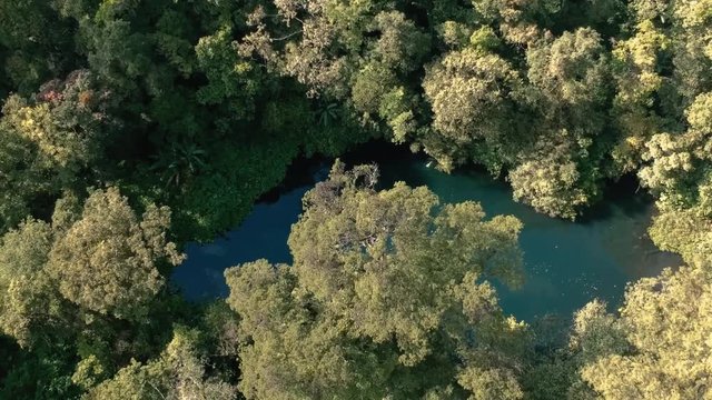 Drone aerial unveiling or revealing shot of the hidden Telaga Biru (Blue Lake) at the forest near Gede Mountain in Java island, Indonesia