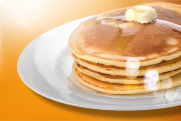 Stack of tasty pancakes with butter on a white plate