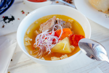 Uzbek chorba - soup from fresh meat and vegetables on white table.