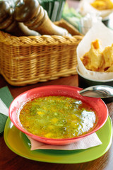 Lentil soup in a red plate over a wooden table.