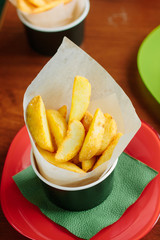 Fried potatoes rolled in parchment over a table.