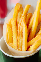 French fries rolled in parchment inside black cup on table.