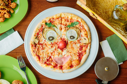 Top view of pizza for kids in a form of funny face.