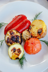 Close up view of grilled vegetables, tomato, potato, pepper, eggplant on white plate.