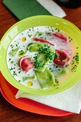 Green and red ravioli in soup for kids.