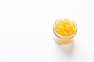 Omega 3 capsules in glass jar on white background Fish oil Yellow softgels Vitamin D, E, A...