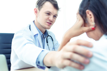 Professional doctor man with stethoscope reassuring woman patient on workplace in hospital.Professional medical doctor comforting patient at consulting room.Medical ethics and trust healthcare concept
