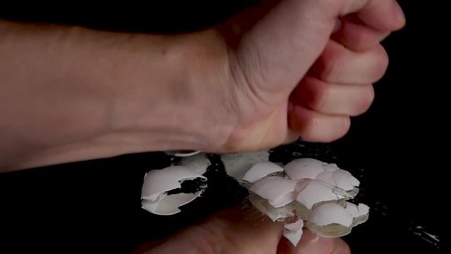 Slow motion shot of smashing a egg shell with a bare hand.