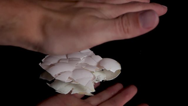 Medium shot of smashing a empty egg shell with bare hand in slow motion.