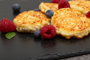 Cheesecakes from cottage cheese. Cottage cheese pancakes or curd fritters decorated fresh raspberries and blueberries. Healthy and diet breakfast. 