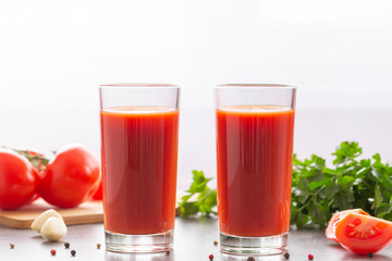 Fresh tomato juice with parsley and spices, selective focus. Glasses with tomato juice and fresh tomatoes on a table 