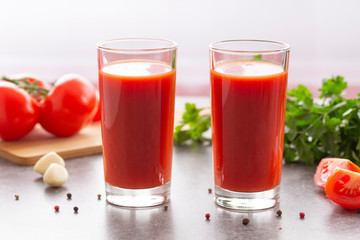 Fototapeta na wymiar Fresh tomato juice with parsley and spices, selective focus. Glasses with tomato juice and fresh tomatoes on a table 