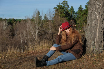 Female model in a red hat and autumn coat in the woods for a walk.