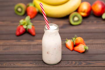 Fruit smoothie with banana, strawberry, kiwi and nectarines on wooden table with fresh ingredients. 