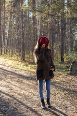 Female model in a red hat and autumn coat in the woods for a walk.