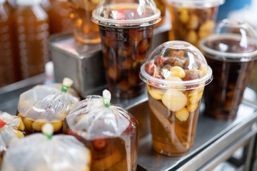 A plastic cup and plastic bag of cold assorted beans, lotus roots, ginkgo, longan and sweet syrup in street food shop in asian for healthy and refresh know as Sweet Taothueng in Thailand.