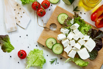 Ingredients for cooking qreek salad with fresh vegetables, feta cheese and black olives on wooden...