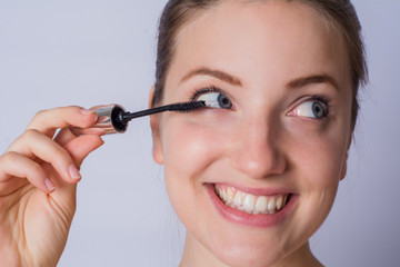 Young woman applying black mascara.