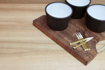 Empty brown ceramic bowls and chopsticks on wooden tray on light background.