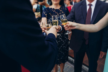 Newlywed bride and groom toasting champagne with friends and family at wedding reception in...
