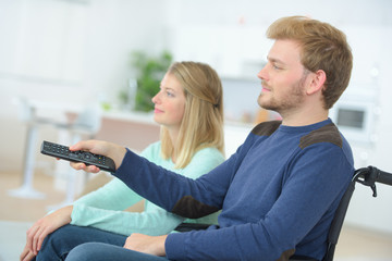 man in wheelchair watching tv with his girlfriend