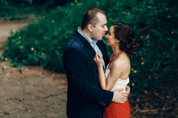 Portrait of happy newlywed couple having fun, funny handsome groom and beautiful bride in elegant dress making faces outdoors in a park