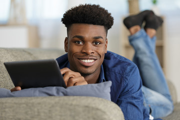 happy man with tablet computer on the sofa