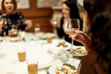 hand of stylish woman holding glass of champagne and toasting at luxury restaurant, space for text
