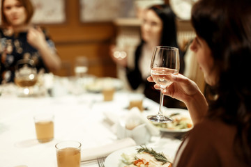 hand of stylish woman holding glass of champagne and toasting at luxury restaurant, space for text