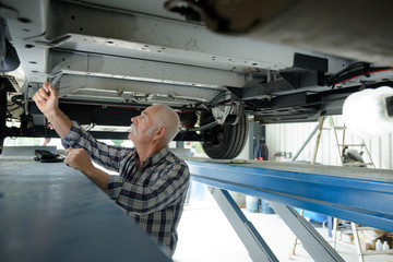 senior mechanic working underneath vehicle