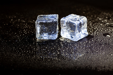 ice cubes reflection on black table background.
