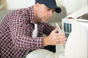 Naklejka na ściany i meble portrait of a man adjusting air conditioning system