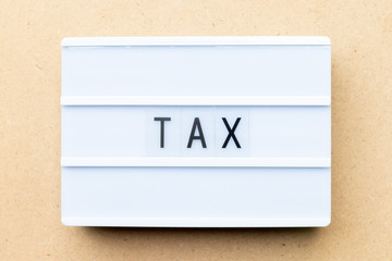 White lightbox with word tax on wood background