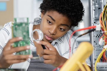 female engineer using solder and magnifying glass