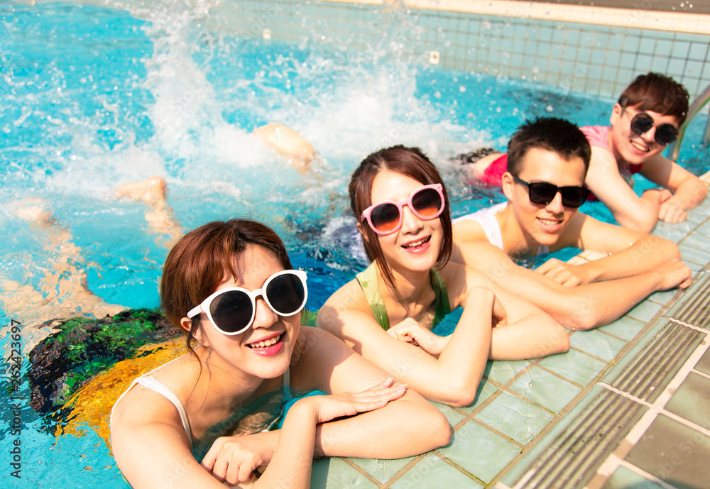 Wall mural Happy friends playing in swimming pool on summer vacation