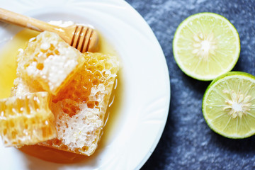 Fresh honey and lemon lime / Close up of yellow sweet honeycomb slice on white plate
