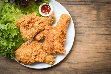 Fried chicken crispy on white plate with ketchup and salad lettuce vegetable on wooden background