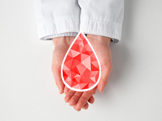 Hands of female doctor with drop of blood on light background