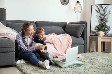 Young mother with little son watching cartoons at home
