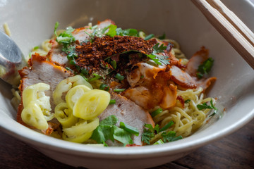 Close up egg noodles with BBQ pork fill pickled chilli and chilli powder.