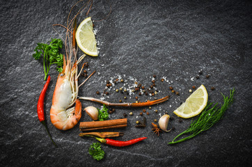 Shrimp prawn cooked shellfish seafood with lemon tomato herbs and spices on dark background