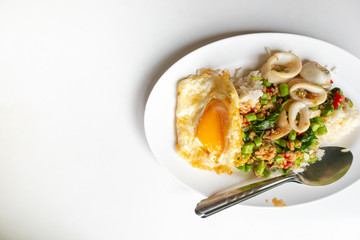 Close up of rice topped with stir-fried pork squid and basil.